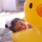 Toddler in duck pool with bubbles in hair for story about Best Toddler Shampoo and Conditioner