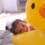 Toddler in duck pool with bubbles in hair for story about Best Toddler Shampoo and Conditioner