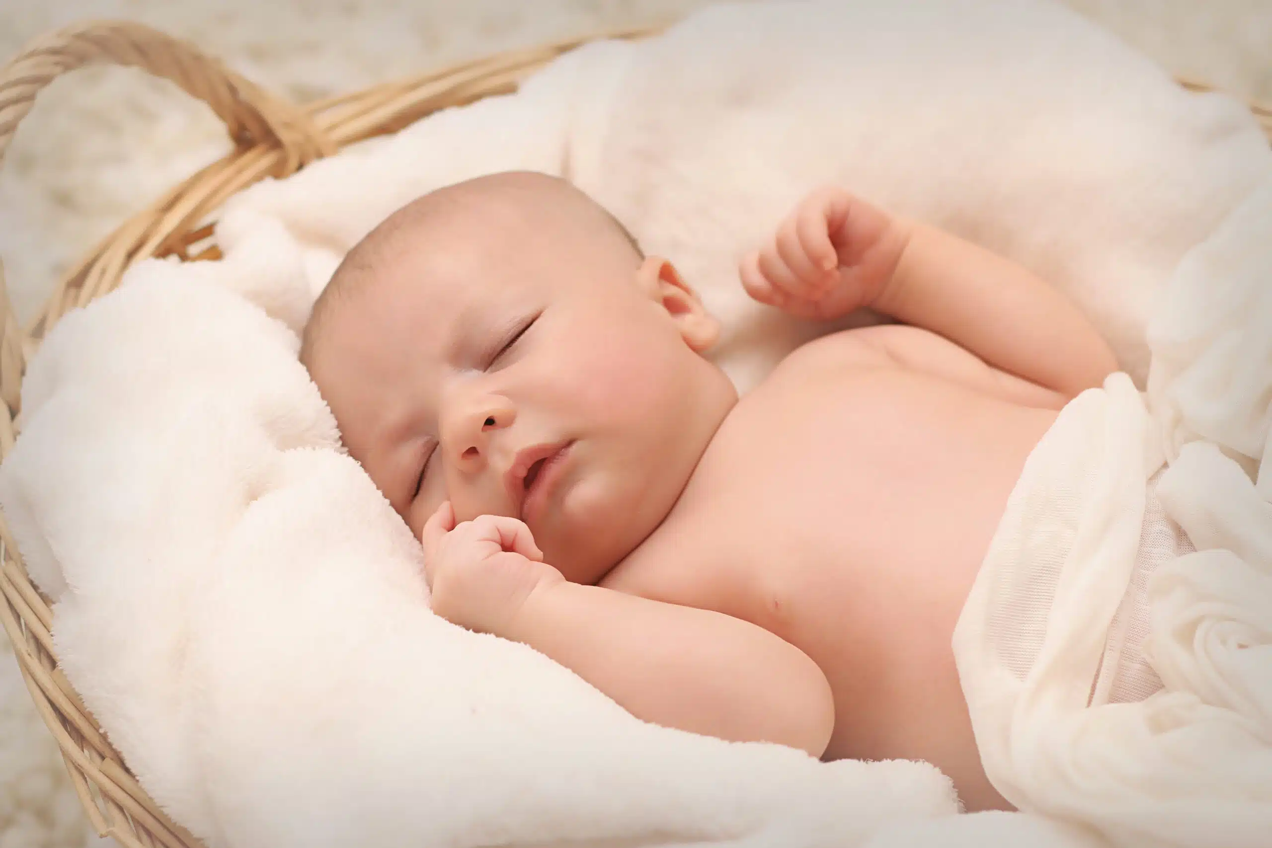 Baby sleeping in basket with fluffy blankets for article about DockATot alternatives.