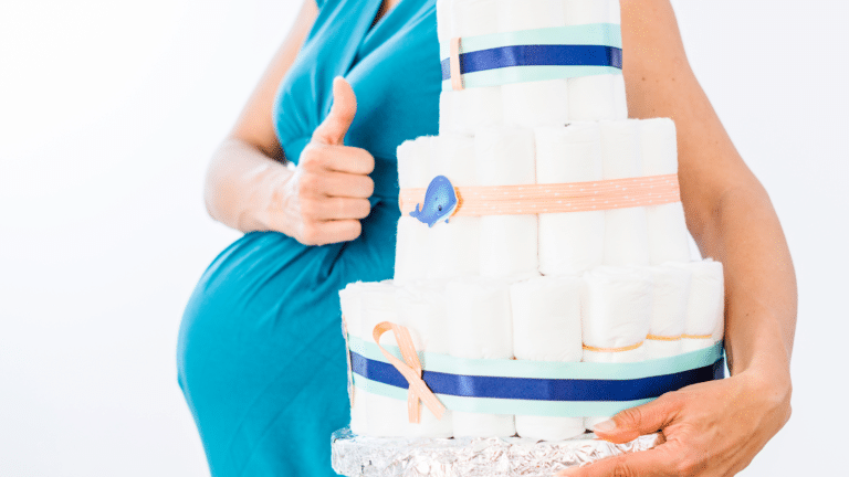pregnant person belly giving thumbs up with a diaper cake for diaper baby shower