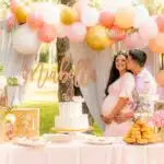 photo of couple with pregnant woman kissing with baby shower decorations for diaper baby shoewr