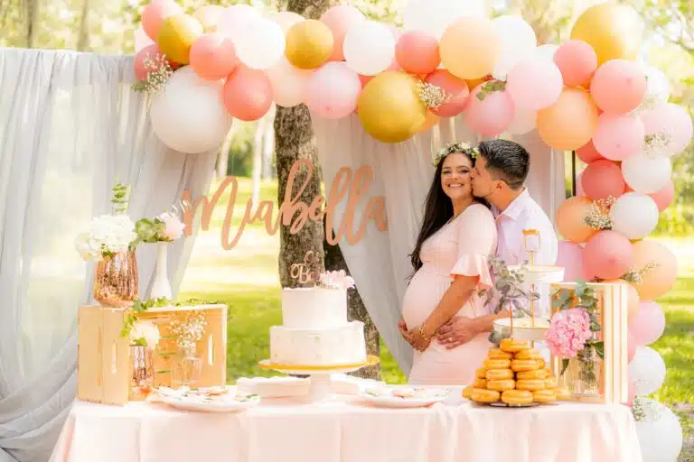 photo of couple with pregnant woman kissing with baby shower decorations for diaper baby shoewr