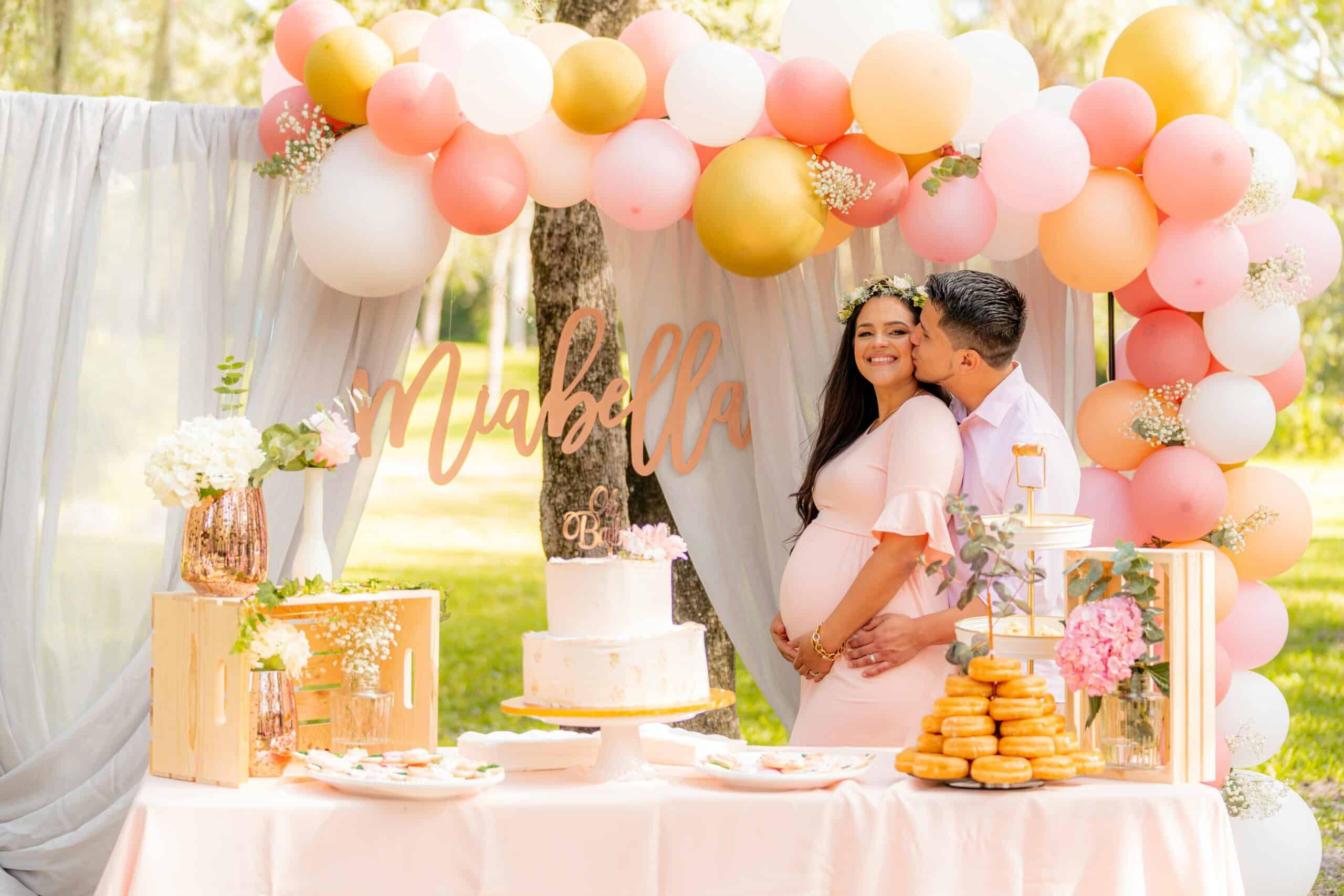 photo of couple with pregnant woman kissing with baby shower decorations for diaper baby shoewr